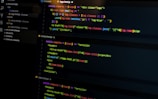 A computer screen displays various sections of code written in JavaScript. The code includes module exports and HTML tags within a text editor interface, which is divided into several panels. The text editor panel exhibits a dark theme with syntax highlighting, showing functions and variables.
