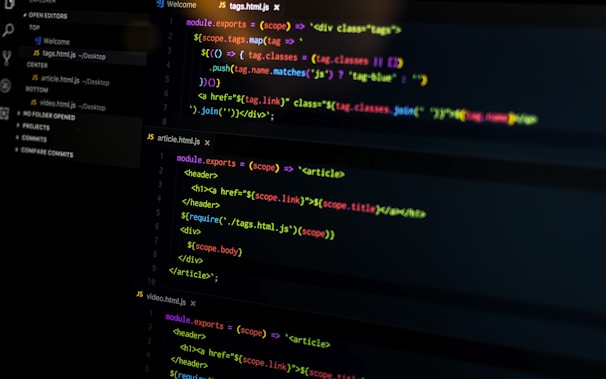 A computer screen displays various sections of code written in JavaScript. The code includes module exports and HTML tags within a text editor interface, which is divided into several panels. The text editor panel exhibits a dark theme with syntax highlighting, showing functions and variables.