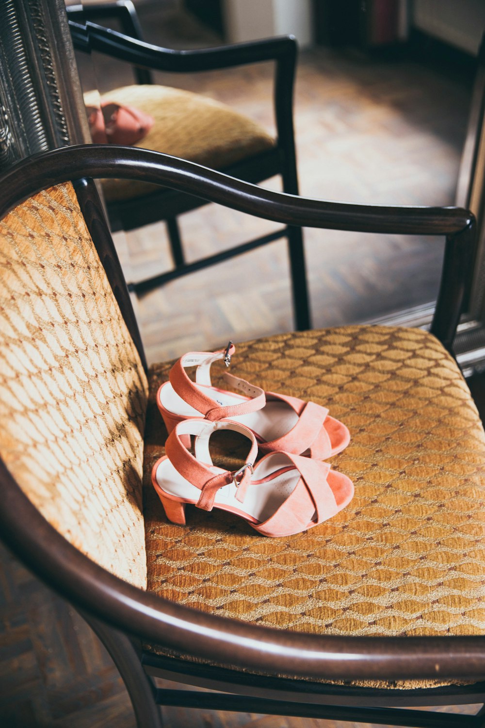pair of pink suede peep-toe chunky-heels sandals on beige wooden armchair