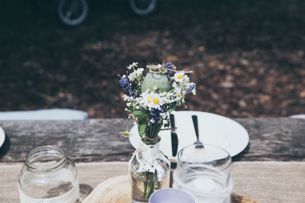 Weiße und blaue Blüten in klarer Glasflasche