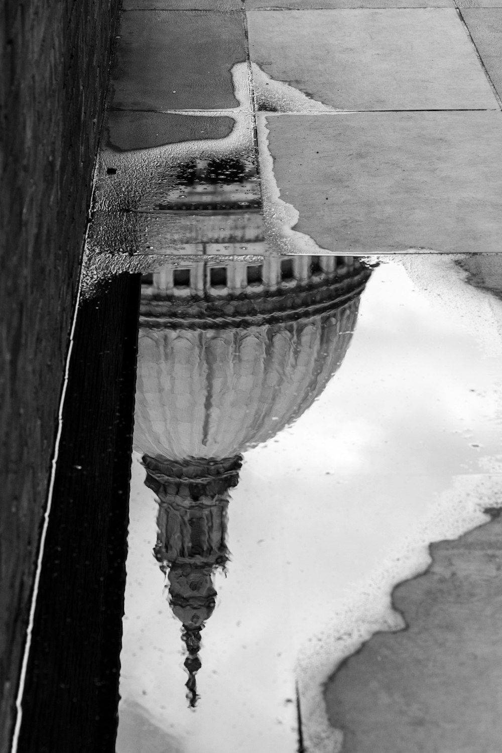 Photo en niveaux de gris d’une flaque d’eau sur le trottoir