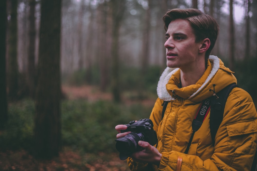 uomo che indossa un parka giallo con fotocamera DSLR