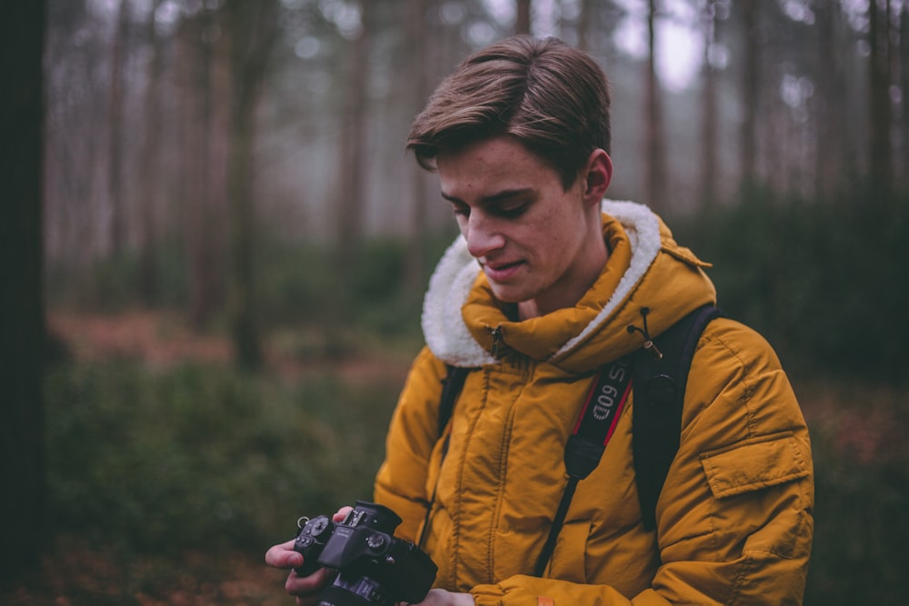 homem em pé segurando DSLR na floresta