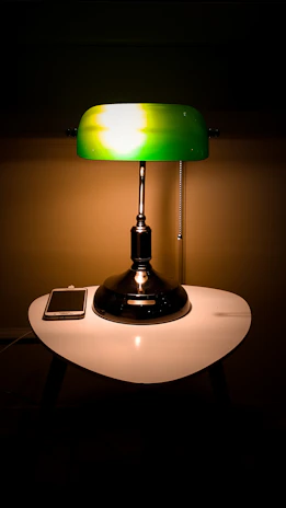 A retro glass table lamp glowing gently on a vintage wooden desk.