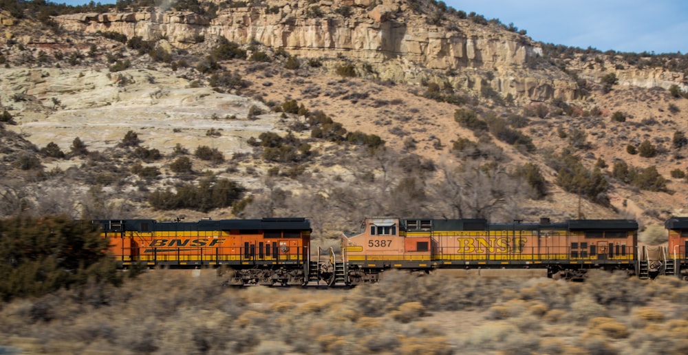 brown and black train on rail near the brown and black mountain during daytime