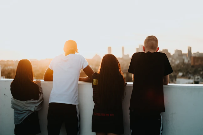 Friends laughing together on a city rooftop at sunset, wearing bold streetwear.