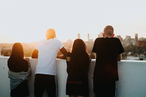Team members discussing progress on a rooftop with city skyline in the background during sunset.