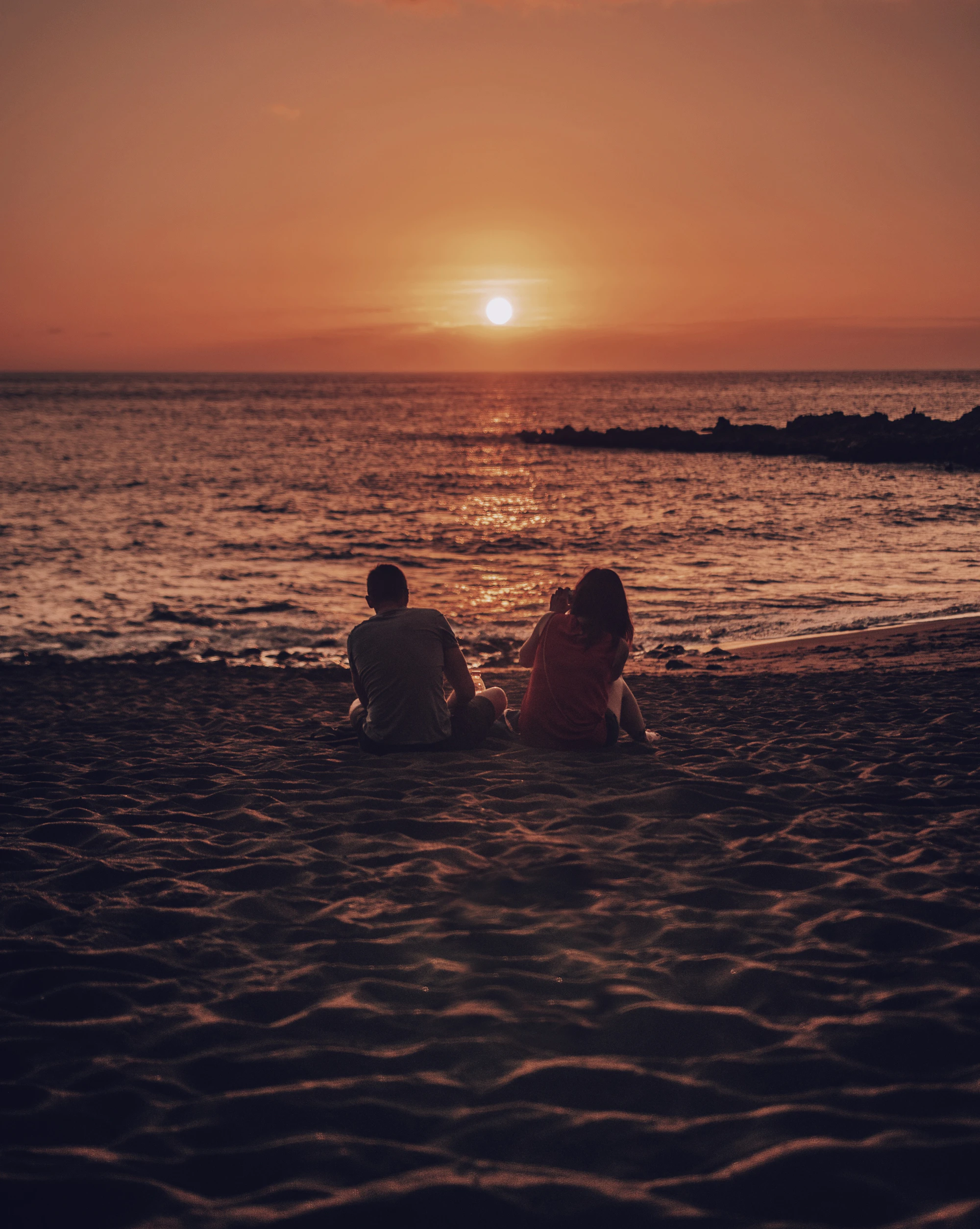 Couple sitting on a beach at golden hour
