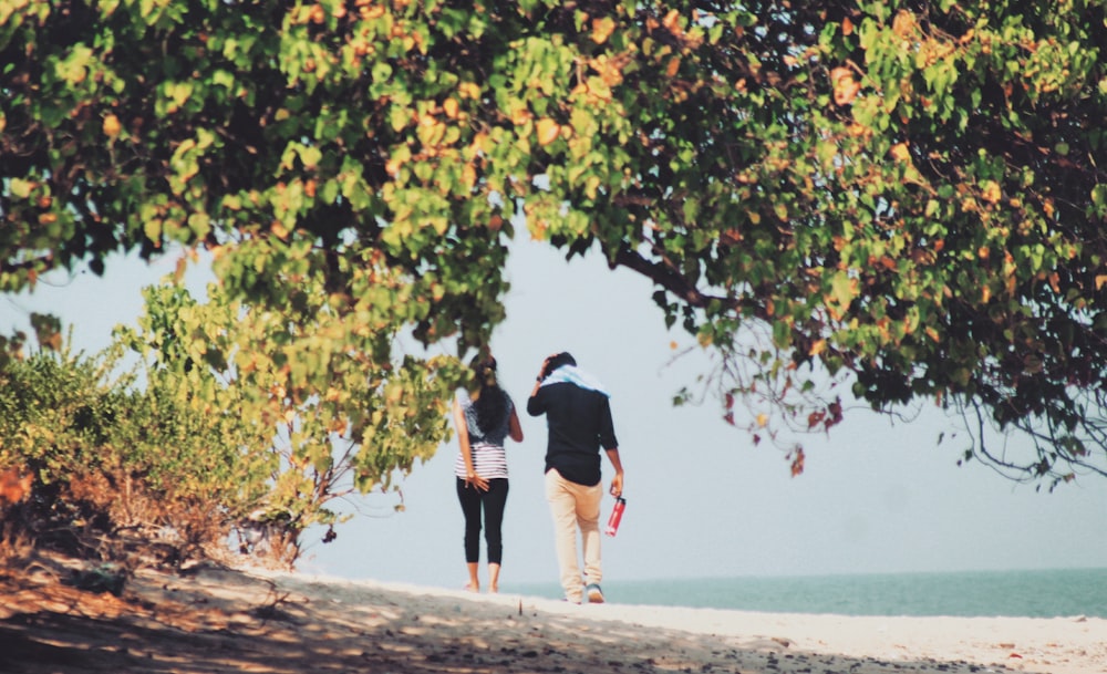 man and woman walking on seashore during daytime