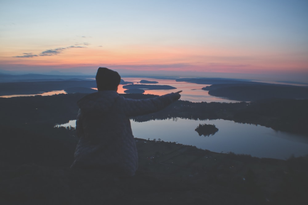 woman sitting on field near body of water