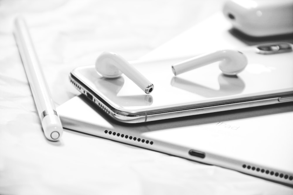 fotografia in scala di grigi di iPhone X, AirPods, Apple Pencil e iPad