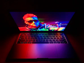 Vibrant image of a man using a laptop with a deep navy and teal gradient softly illuminating the scene