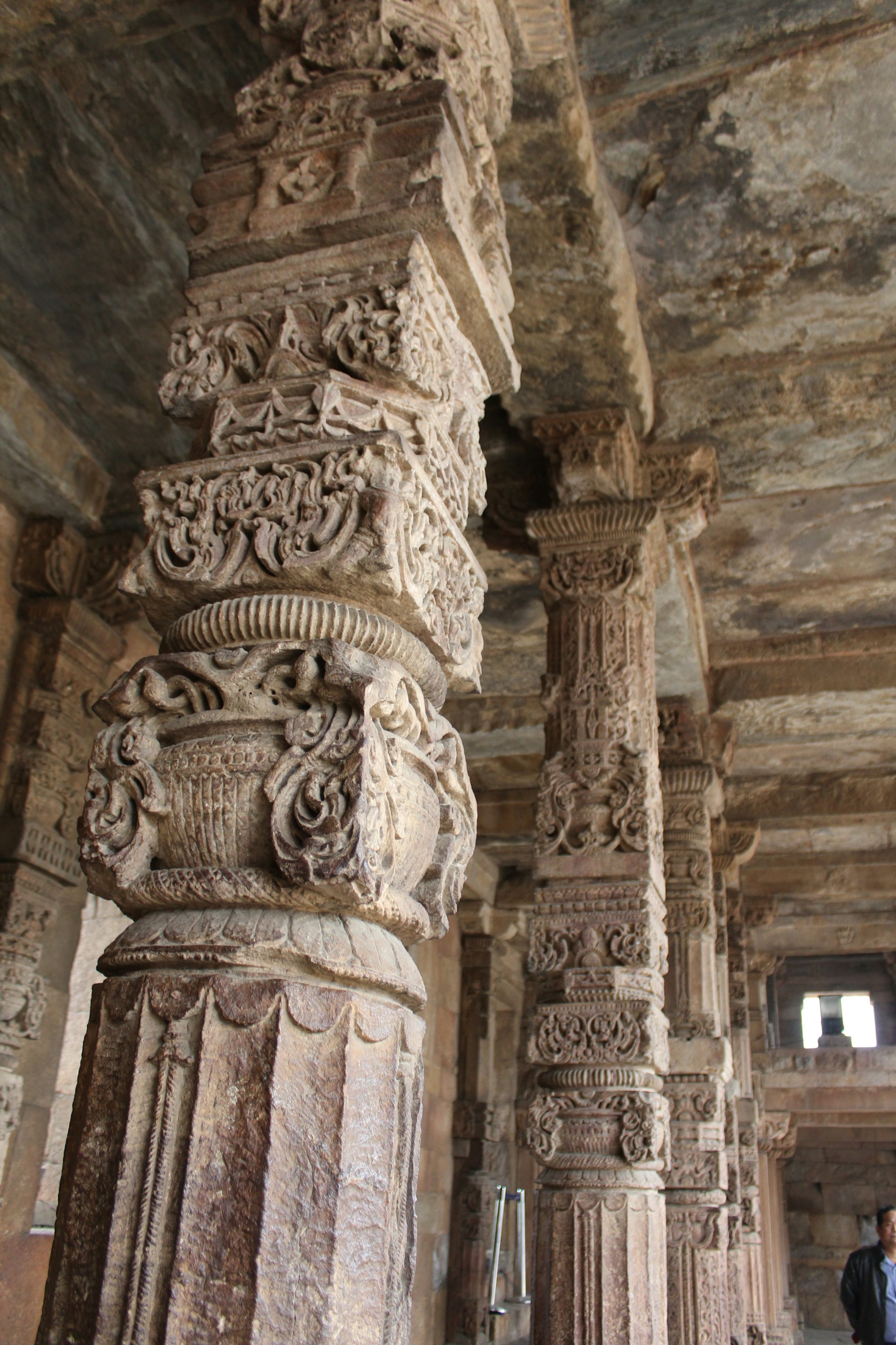 Skilled artisans at the Dhrangadhara factory carefully shaping intricate temple pillars with hand tools.