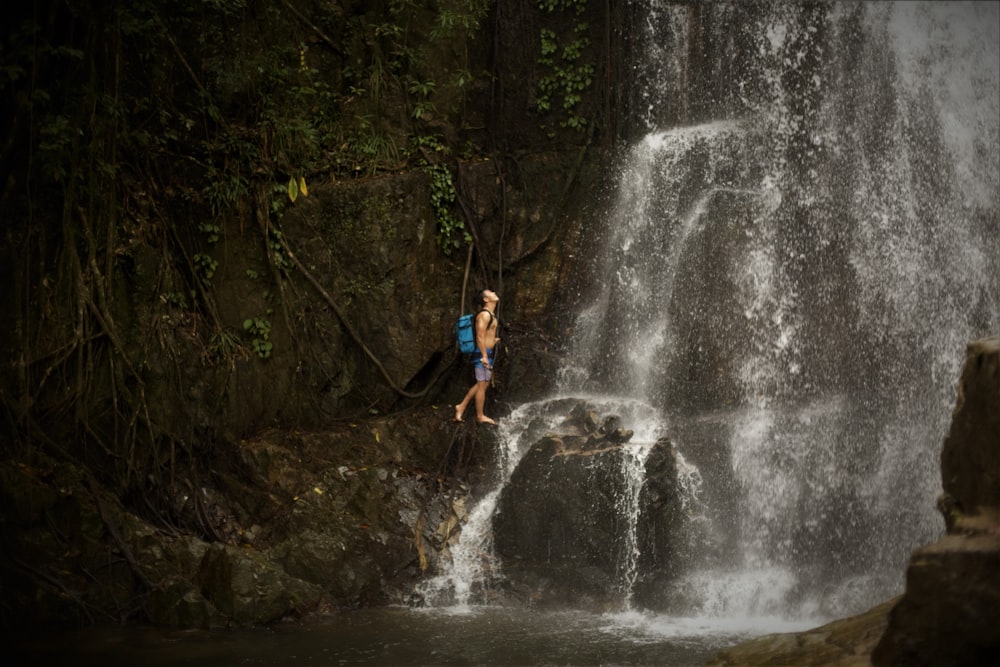 man standing near waterfalls during daytime
