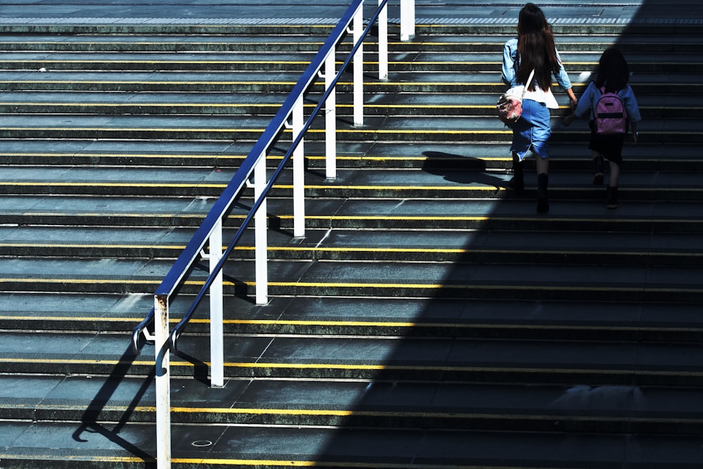 woman holding girl walking on stairs