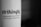 A close-up of black text printed on a white curved surface, with the text reading: 'strikingly' and 'CONQUER THE WORLD WITH JUST ONE PAGE'. The background fades into a dark gradient.