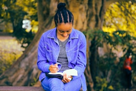 selective focus photography of woman reading book while sitting at bench