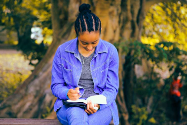 selective focus photography of woman reading book while sitting at bench