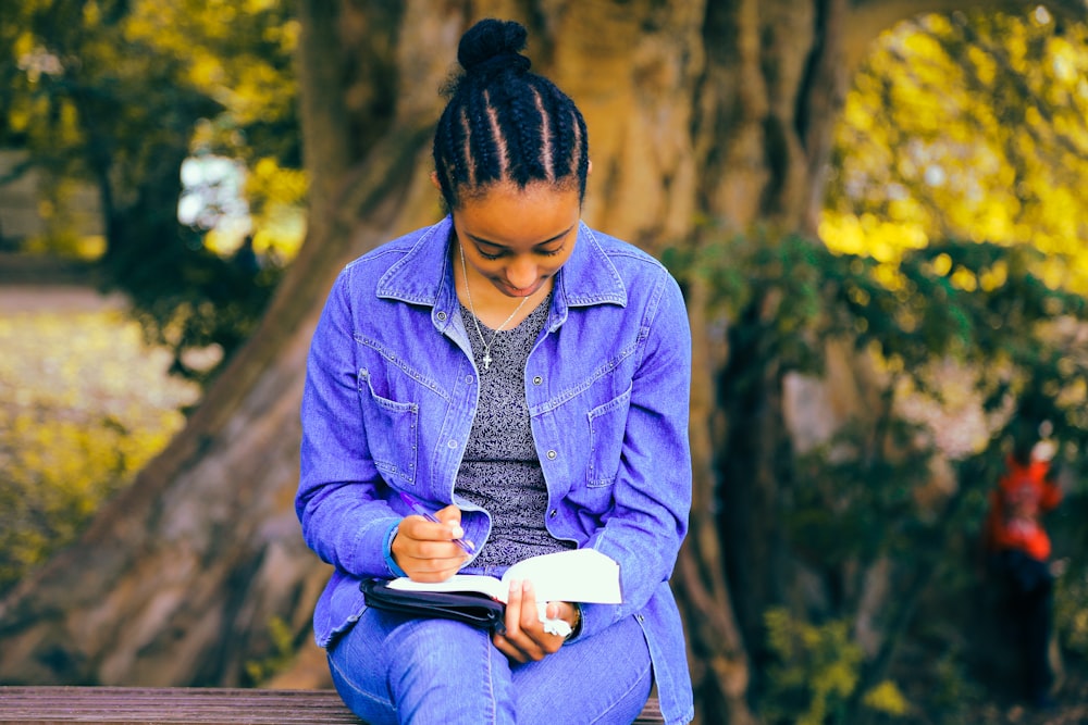 Photographie sélective de la femme lisant un livre alors qu’elle est assise sur un banc