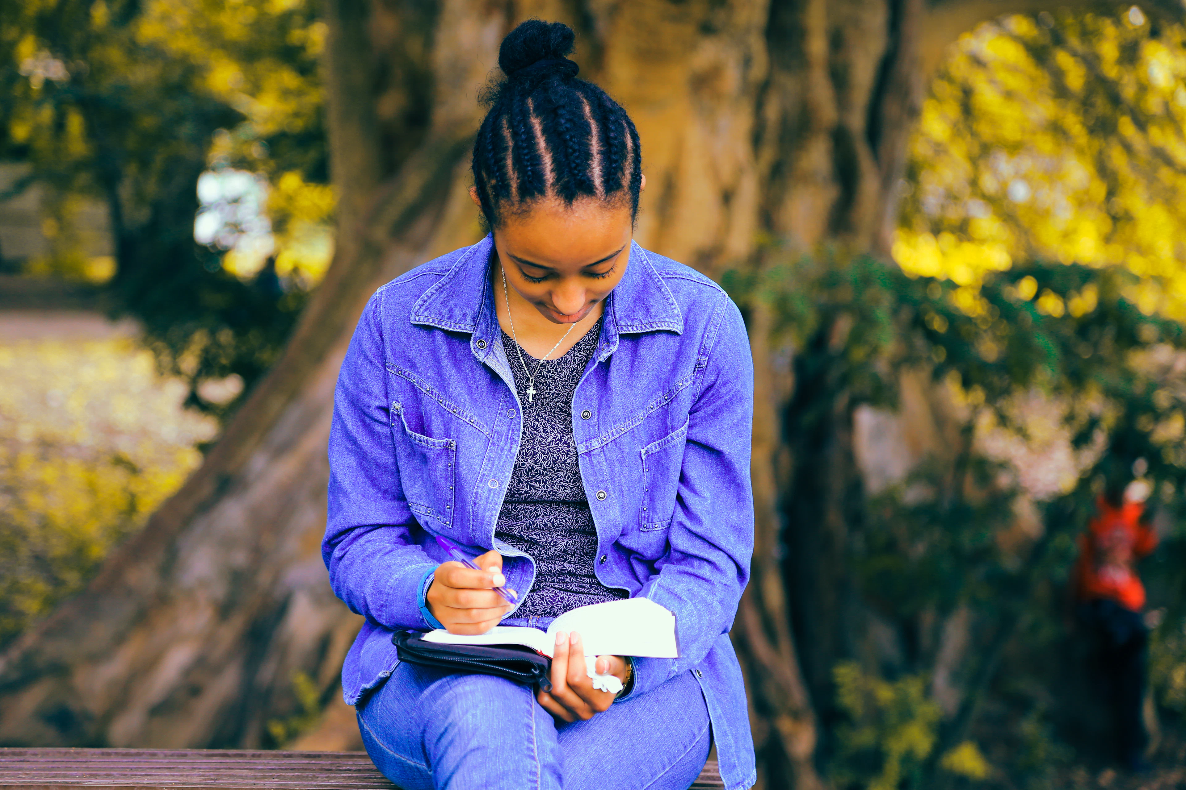 Étudiante qui lit un livre sur un banc dans un parc