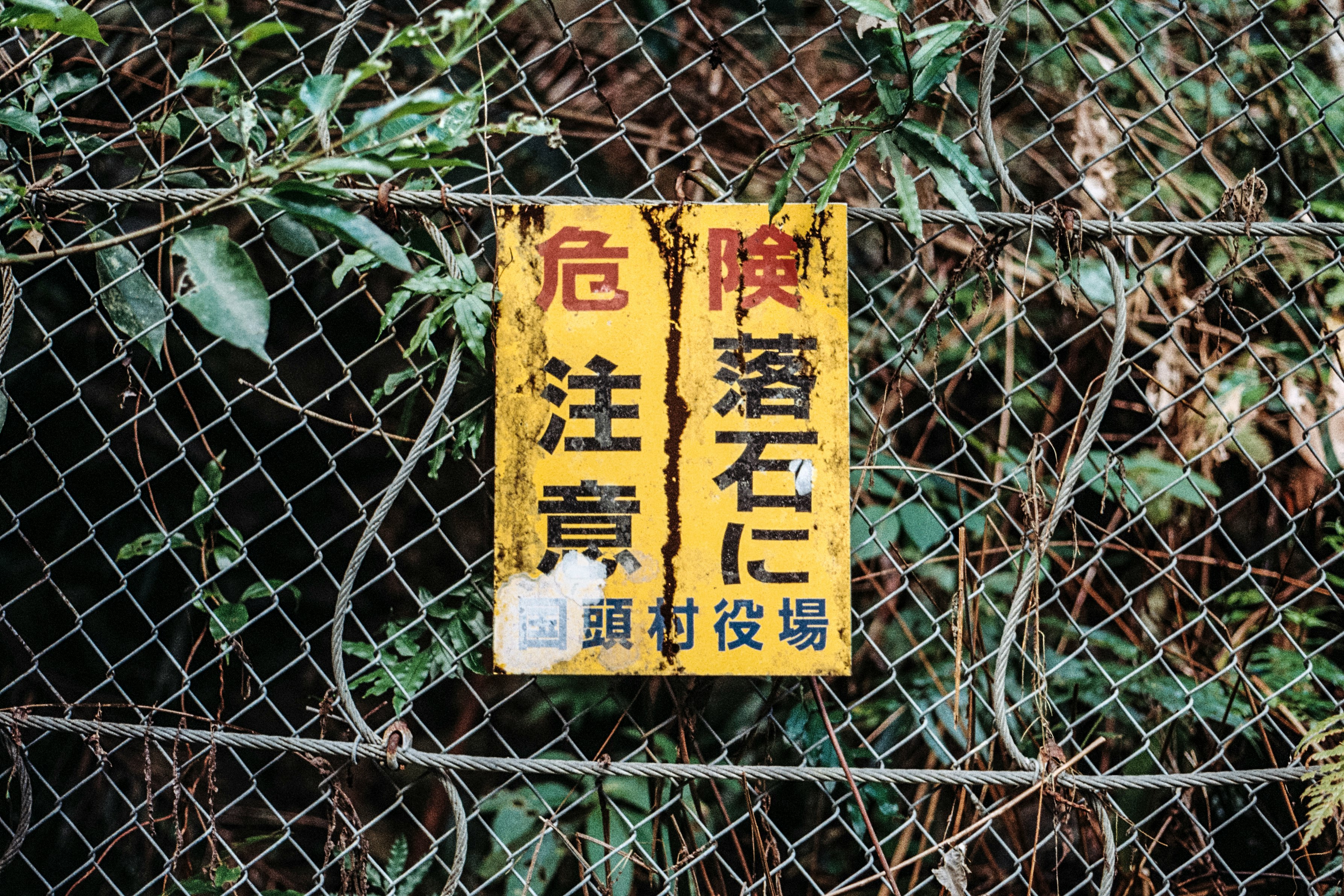 kanji labeled signage hanged on wire fence