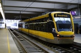 A modern yellow and black metro train is stationed on sleek, well-maintained tracks at an indoor railway platform.