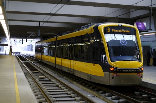A modern yellow and black metro train is stationed on sleek, well-maintained tracks at an indoor railway platform.