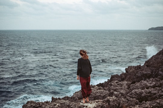 woman standing at seashore cliff in Cape Hedo Japan