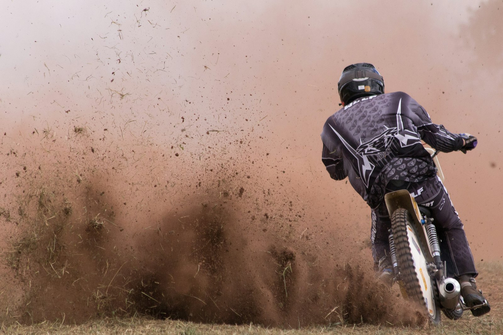 Dirt bike rider kicking up a roost of dust and dirt