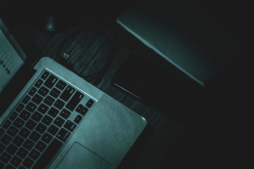A professional workspace with a laptop and notepad on a dark table.