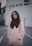 woman wearing pink pullover hoodie standing near wall