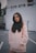 woman wearing pink pullover hoodie standing near wall