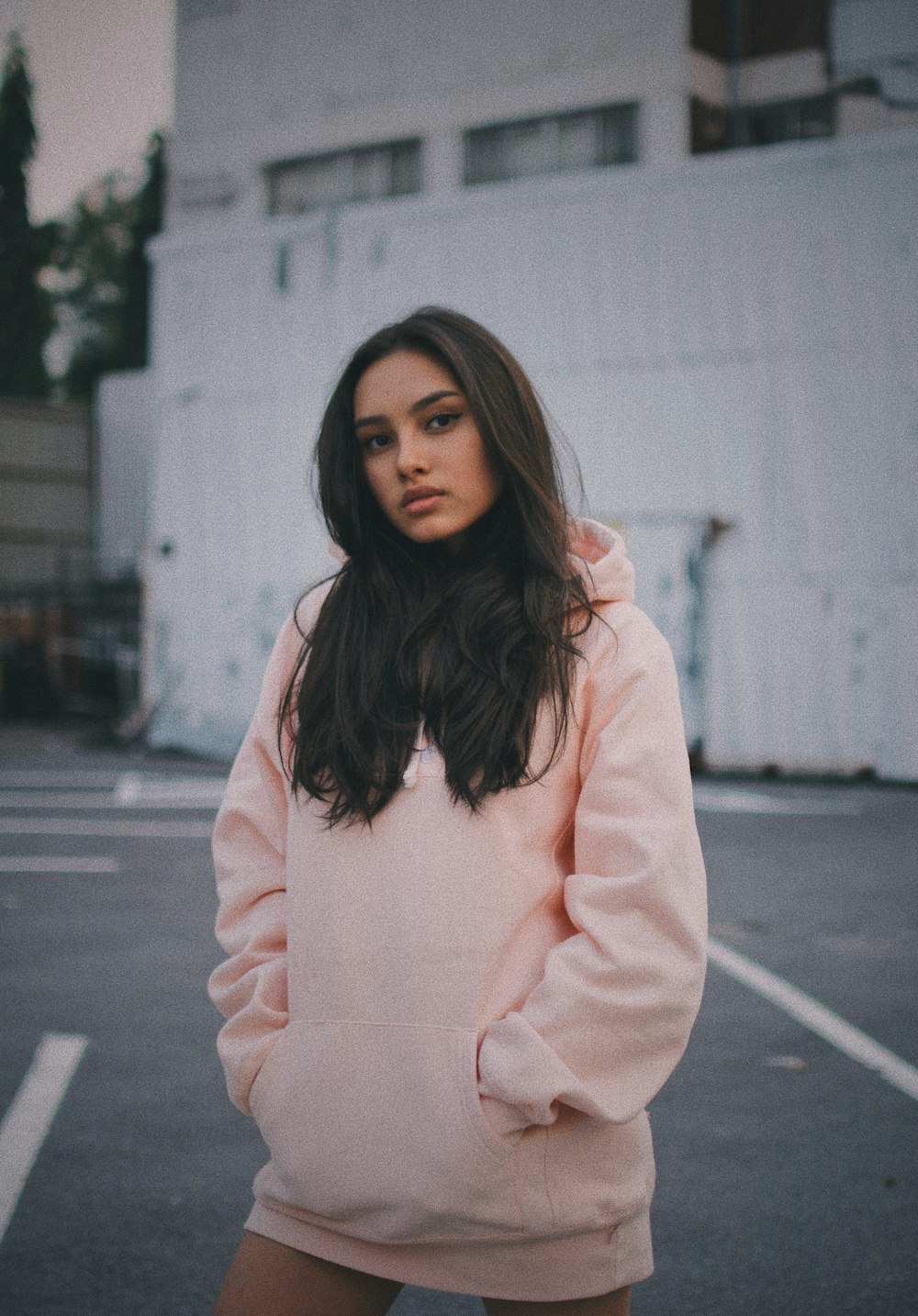 woman wearing pink pullover hoodie standing near wall