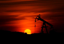 oil pump jack silhouette against red sunset