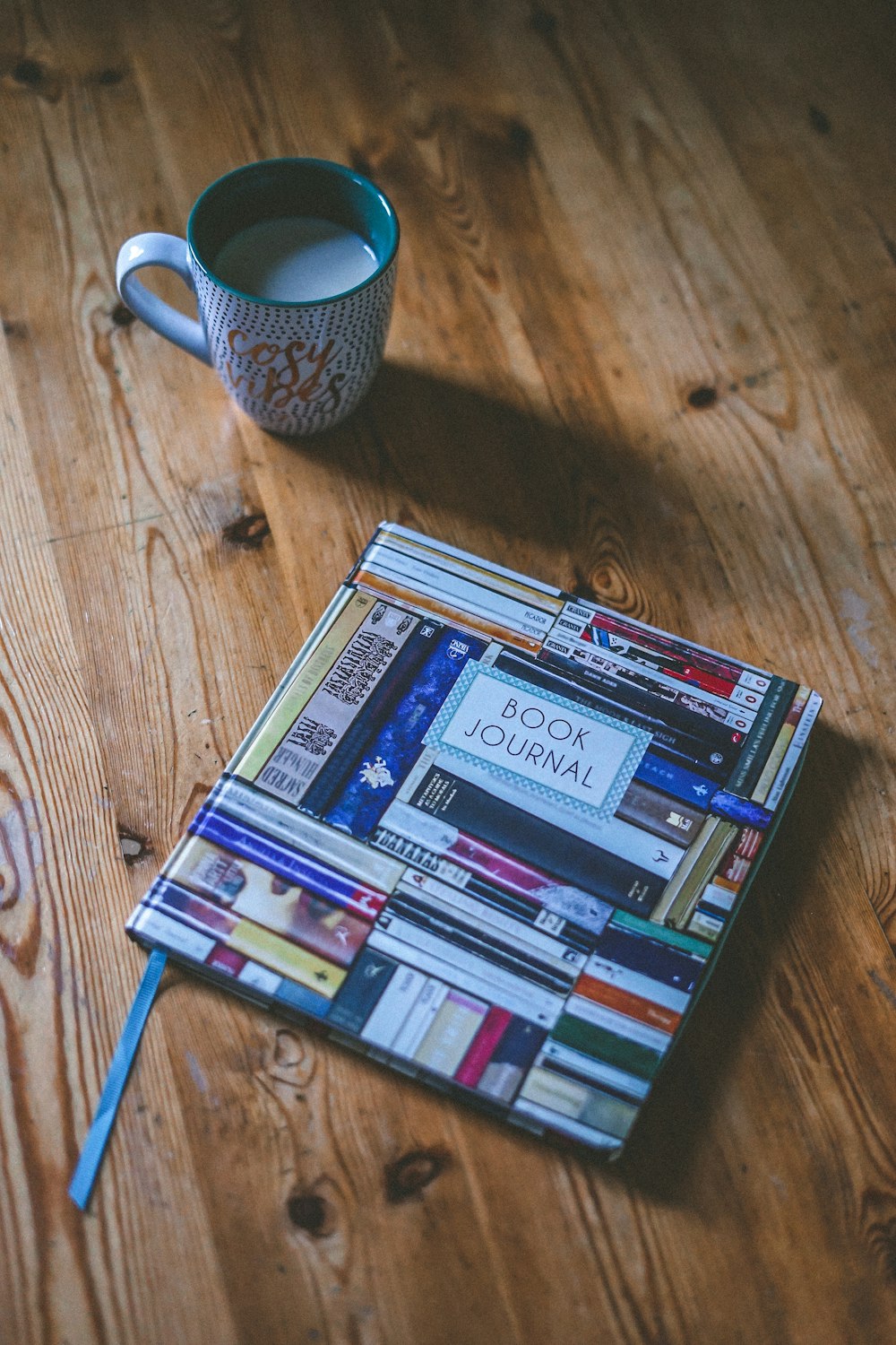 Journal de livre près de la tasse en céramique blanche et multicolore sur une surface en bois