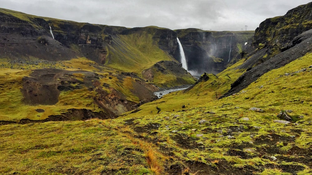 waterfalls near grass field during daytime