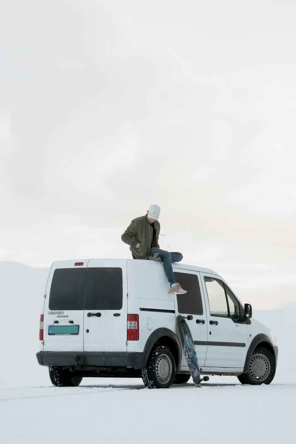 man sitting on top of white minivan during daytime
