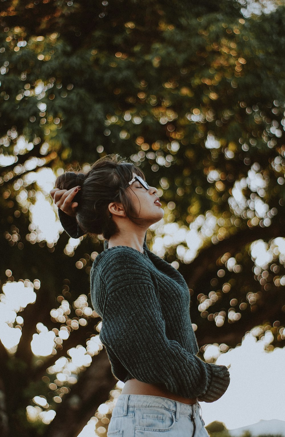 나무 근처에서 회색 스웨터를 입고 있는 여자