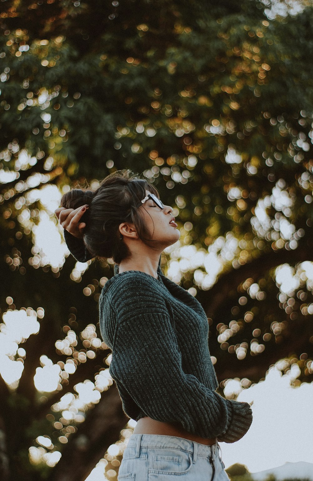 woman wearing gray sweater near tree