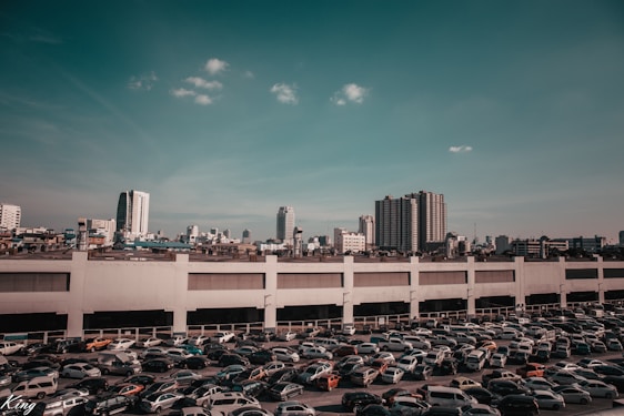 A spacious parking lot filled with parked cars under a clear blue sky.