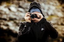 man wearing hoodie taking pictures selective focus photography
