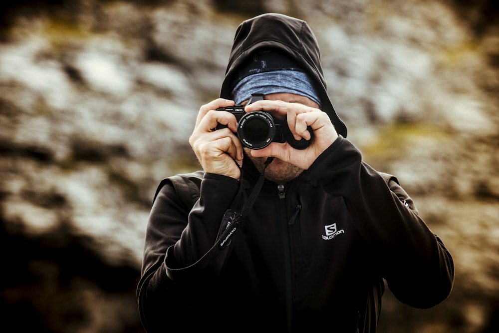 man wearing hoodie taking pictures selective focus photography