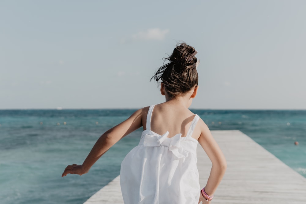 girl running on dock under white sky