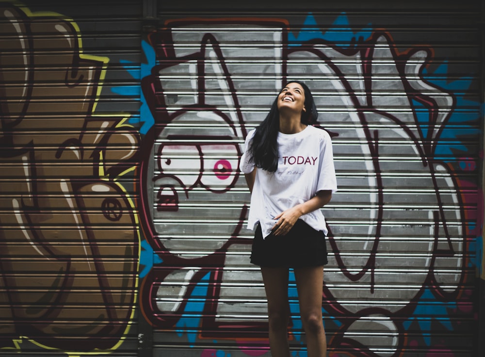 Femme debout à côté d’un mur de graffitis pris de jour