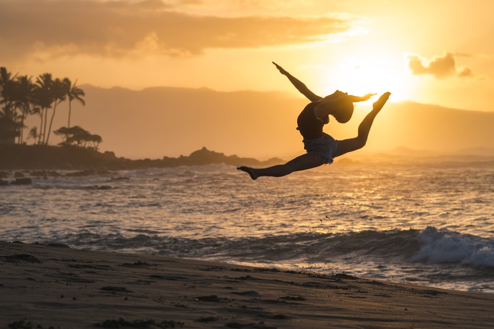 silhouette of woman jumping on sea shore