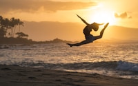 silhouette of woman jumping on sea shore