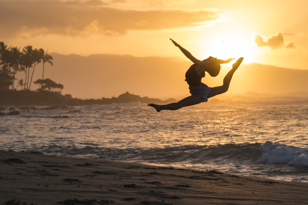 海岸に飛び跳ねる女性のシルエット