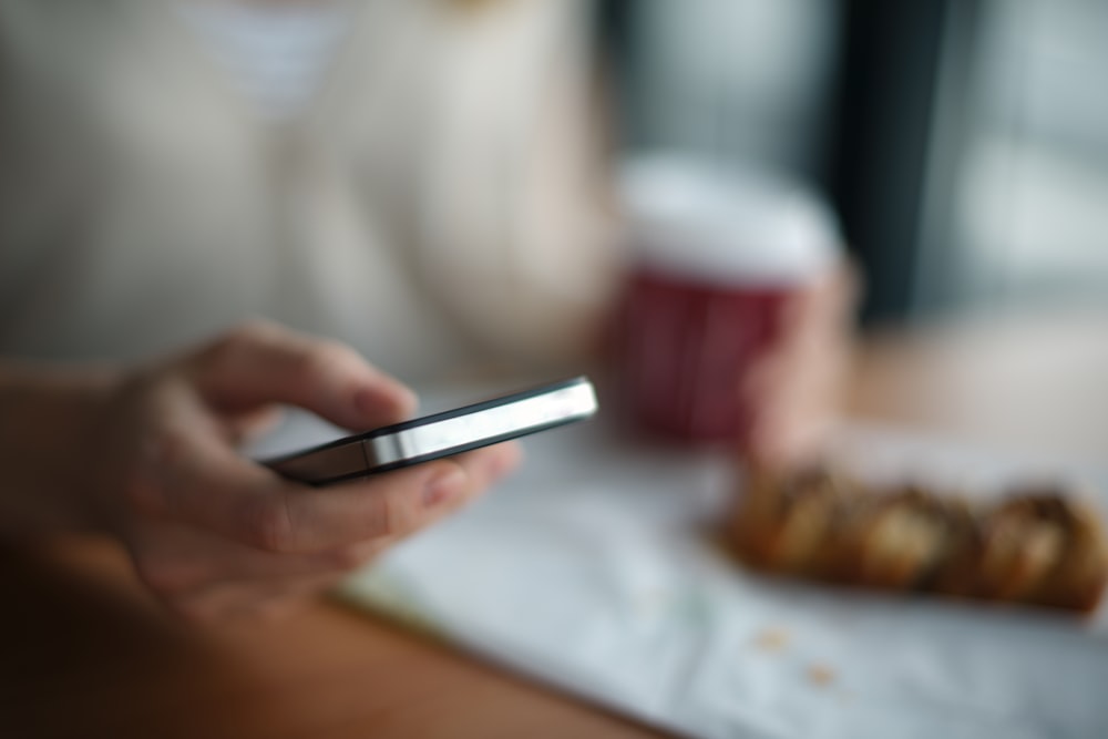 Selektive Fokusfotografie einer Person, die ein graues Telefon hält