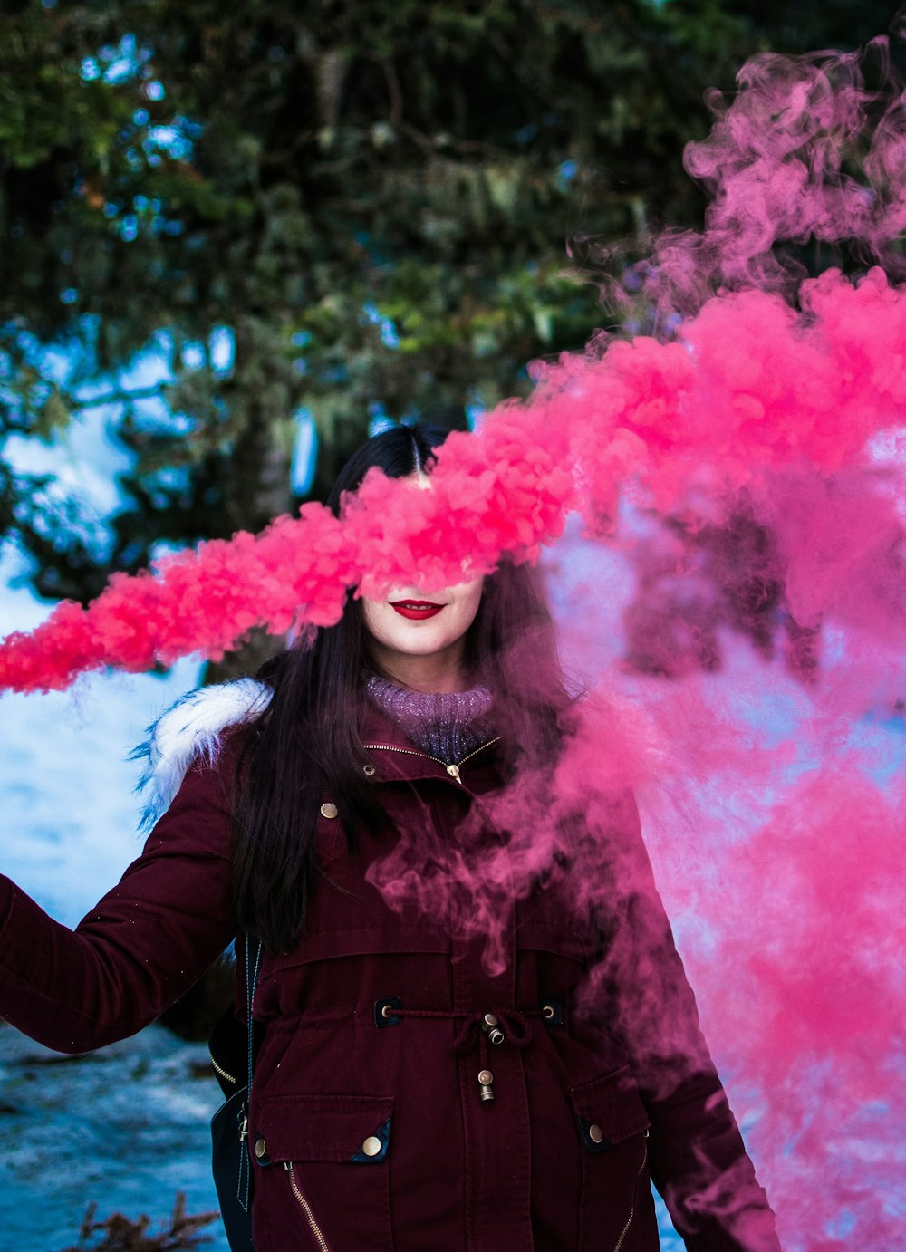 Mujer con parka roja usando cortina de humo
