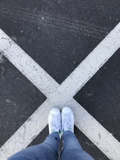 Side view of a white sneaker with black accents on a textured asphalt surface.